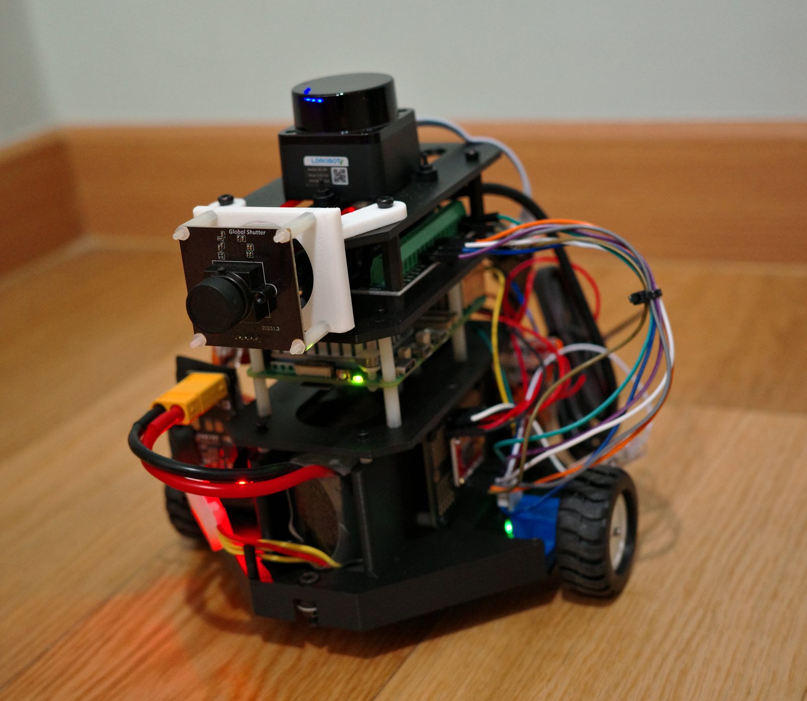 The Lab Scout rover on a wood floor: LiDAR on top, global-shutter camera, stacked boards and wiring
